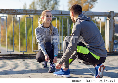 smiling couple tying shoelaces outdoors smiling couple tying shoelaces outdoors 20170351