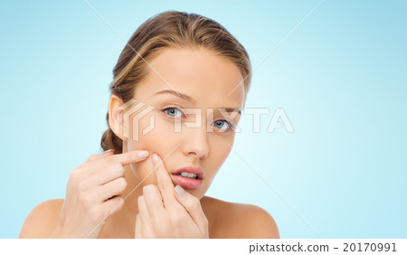 young woman squeezing pimple on her face 20170991