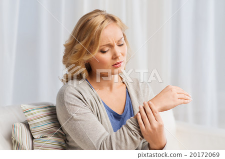 unhappy woman suffering from pain in hand at home unhappy woman suffering from pain in hand at home 20172069
