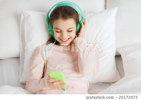 happy girl lying in bed with smartphone at home 20172073