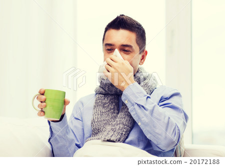 ill man with flu drinking tea and blowing nose ill man with flu drinking tea and blowing nose 20172188