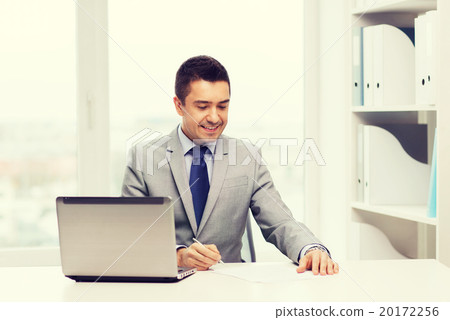 smiling businessman with laptop and papers 20172256