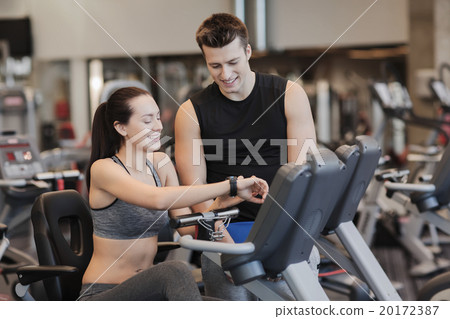 happy woman with trainer on exercise bike in gym happy woman with trainer on exercise bike in gym 20172387