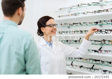 optician showing glasses to man at optics store optician showing glasses to man at optics store 20172485