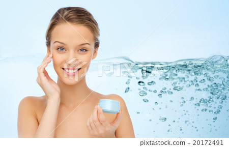 smiling young woman applying cream to her face smiling young woman applying cream to her face 20172491