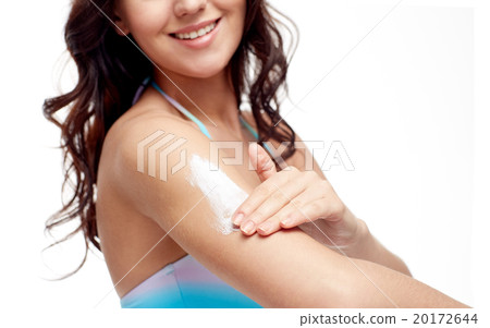 happy young woman in swimsuit applying sunscreen 20172644