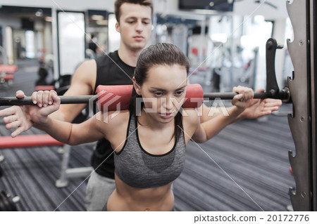 man and woman with barbell flexing muscles in gym man and woman with barbell flexing muscles in gym 20172776