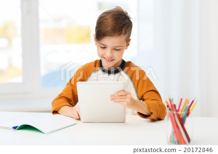 smiling boy with tablet pc and notebook at home 20172846