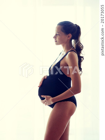 happy pregnant woman near window at home 20173055