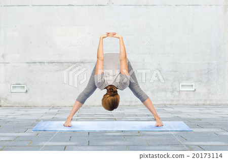 woman making yoga wide-legged forward bend on mat woman making yoga wide-legged forward bend on mat 20173114