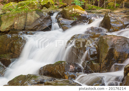 Water falls over a jumble of moss-covered boulders Water falls over a jumble of moss-covered boulders 20176214