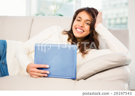 Smiling woman using her tablet on couch 20197543