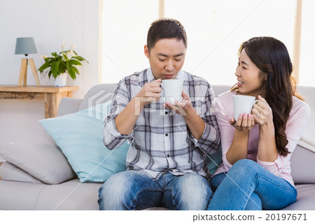 Happy woman looking at man while holding coffee cup 20197671