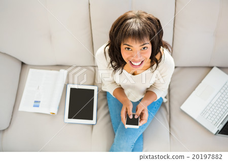 Smiling woman texting on her smartphone Smiling woman texting on her smartphone 20197882