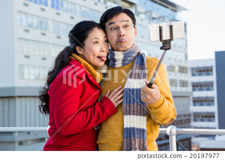 Older asian couple on balcony taking selfie 20197977