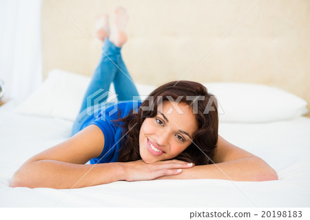 Smiling woman using smartphone while lying on bed 20198183