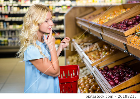 Thoughtful woman looking at onions 20198213