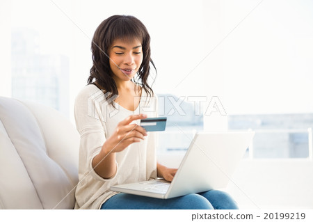 Smiling casual woman buying things with her laptop 20199219