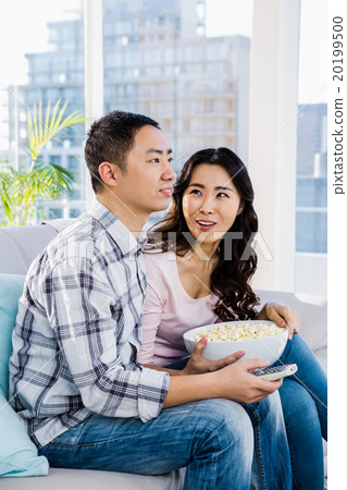 Happy woman looking at man while sitting on sofa 20199500