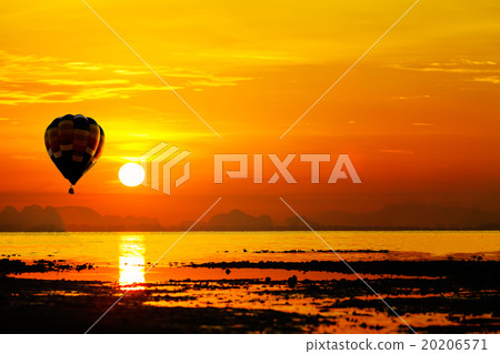 Balloon flying into sunset over the sea. 20206571