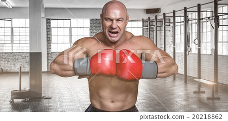 Composite image of angry bald boxer with punching gloves Composite image of angry bald boxer with punching gloves 20218862