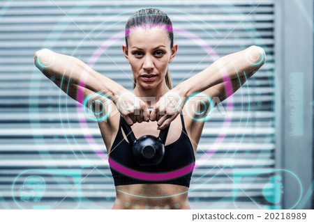 Composite image of a muscular woman lifting kettlebells 20218989