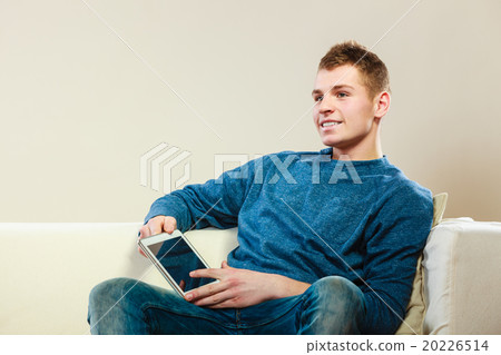 Young man with digital tablet sitting on couch 20226514
