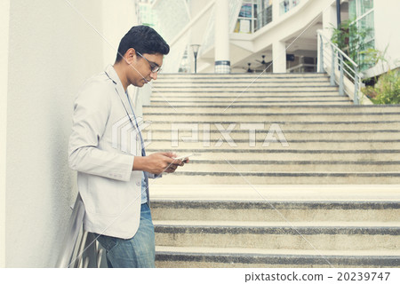 casual indian male using tablet outdoor casual indian male using tablet outdoor 20239747