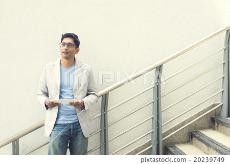 casual indian male using tablet outdoor casual indian male using tablet outdoor 20239749