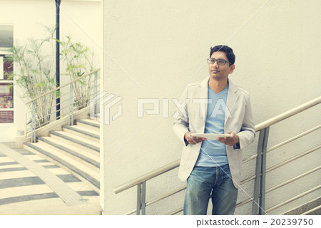 casual indian male using tablet outdoor casual indian male using tablet outdoor 20239750