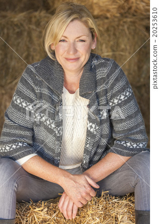 Middle Aged Blond Woman Sitting on Hay Bale 20253610