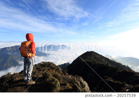 young determined woman backpacker hiking on mountain peak 20257539