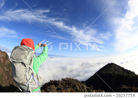 young asian woman backpacker taking photo with smartphone on mountain peak 20257759