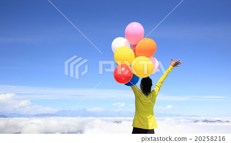 young cheering woman with colorful balloons on mountain peak young cheering woman with colorful balloons on mountain peak 20258216
