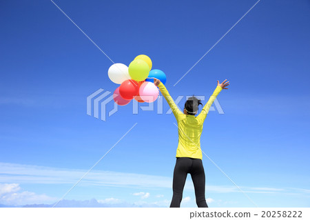 young cheering woman with colorful balloons on mountain peak young cheering woman with colorful balloons on mountain peak 20258222
