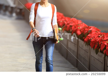 young woman skateboarder walking with skateboard 20258899