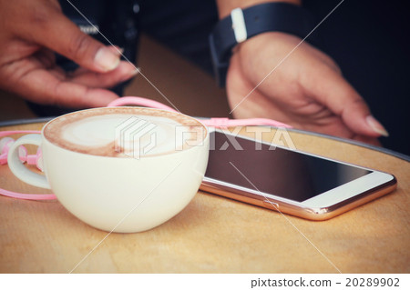 Woman playing smartphone with earphone and coffee Woman playing smartphone with earphone and coffee 20289902