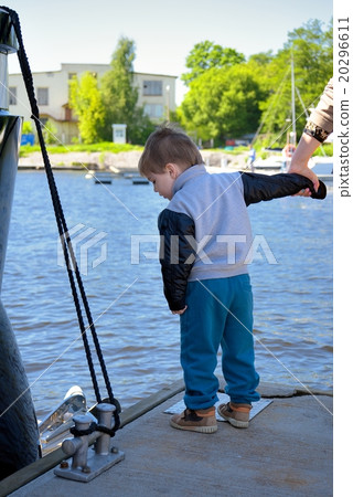 Small child stays on pier and holds mother by hand 20296611