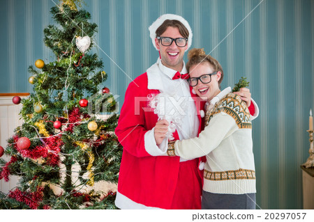 Composite image of geeky hipster in santa costume hugging his gi Composite image of geeky hipster in santa costume hugging his gi 20297057