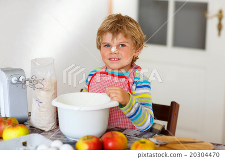 Funny blond kid boy baking apple cake indoors Funny blond kid boy baking apple cake indoors 20304470