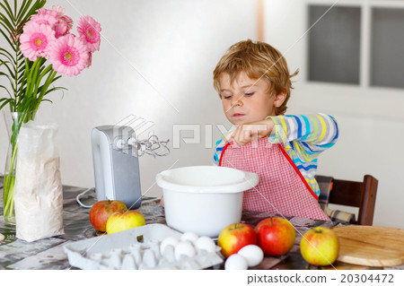 Funny blond kid boy baking apple cake indoors Funny blond kid boy baking apple cake indoors 20304472