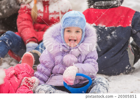 Five-year girl sitting in the snow surrounded by other children 20305851