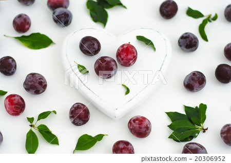 White wooden heart and ripe juicy plums on a white 20306952