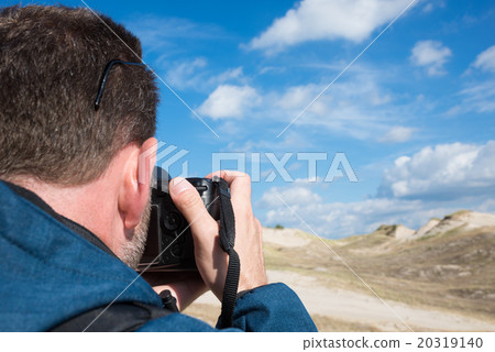 Rear view of a man photographying landscape with digital camera Rear view of a man photographying landscape with digital camera 20319140