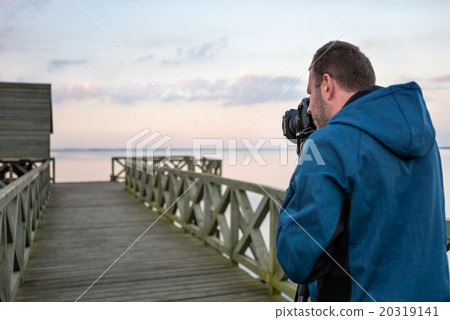 Nature photographer taking photos of the lake at sunset Nature photographer taking photos of the lake at sunset 20319141
