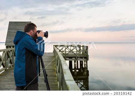 Nature photographer taking photos of the lake at sunset 20319142