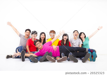 Happy young group sitting together against white wall 20325323