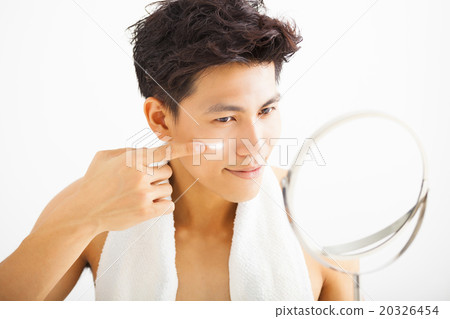 smiling man applying cream lotion on face 20326454