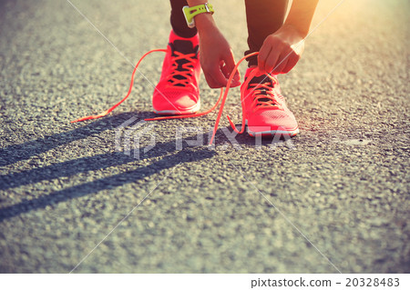 young woman runner tying shoelace on city road 20328483