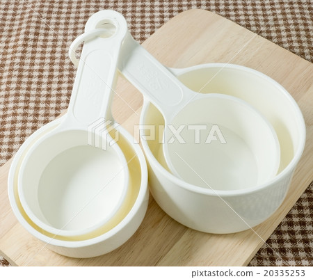 White Plastic Measuring Cups on Wooden Board White Plastic Measuring Cups on Wooden Board 20335253